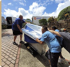 Oahu piano movers carefully load a piano onto a moving truck.