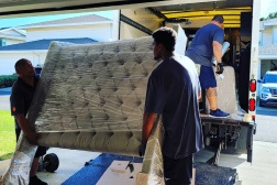 Residential movers load a mattress into a moving truck.
